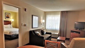 A hotel room with a bed, a sofa, a TV, and a desk. - Candlewood Suites Macon by IHG (Macon)