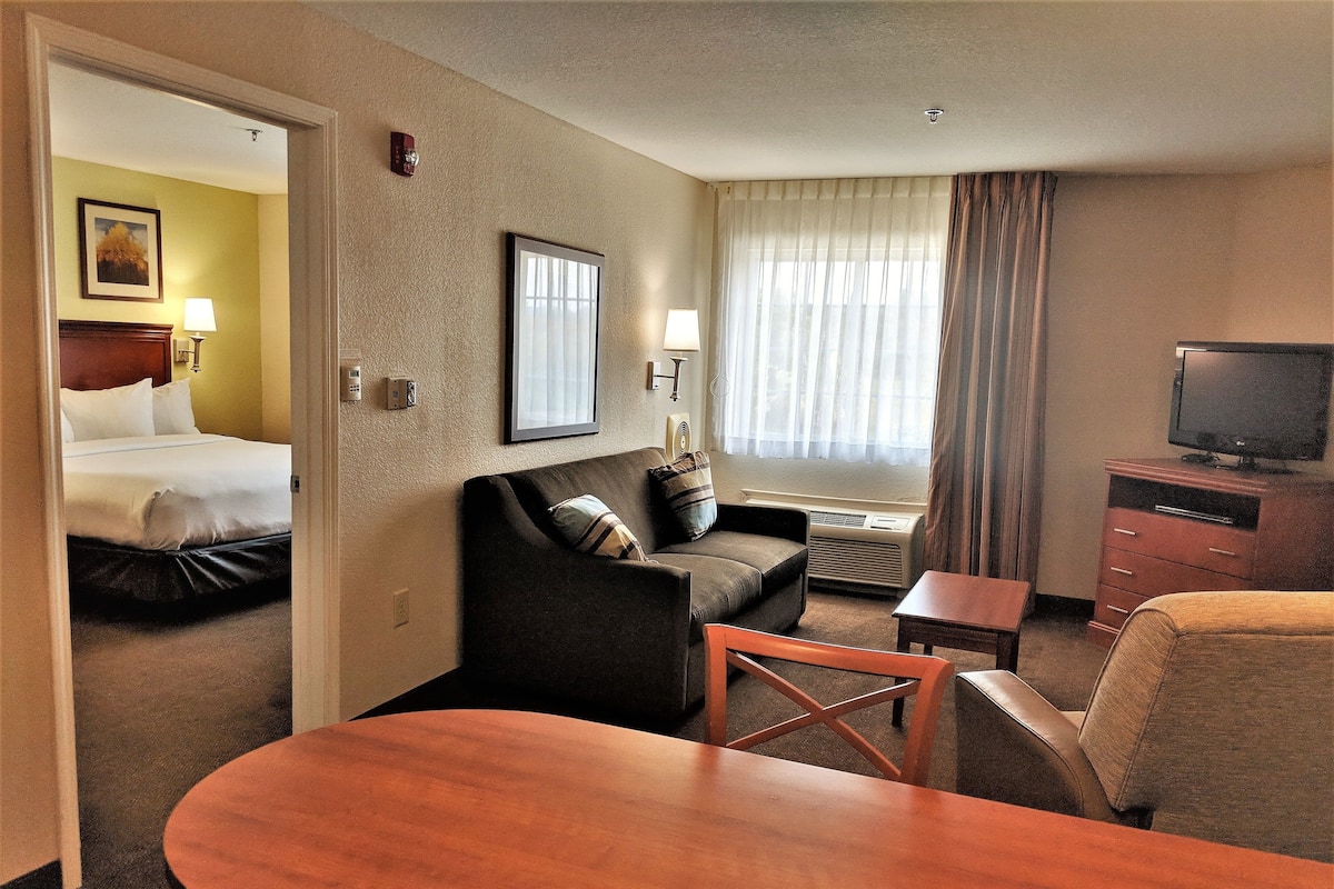 A hotel room with a bed, a sofa, a TV, and a desk.