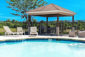 Una piscina con sillas de descanso y un pabellón.