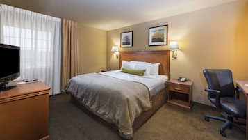 Una habitación de hotel con una cama grande, un escritorio con computadora, un televisor y una silla.