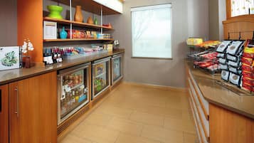 A clean, well-organized snack bar with refrigerated display cases, shelves stocked with snacks, and a window providing natural light.