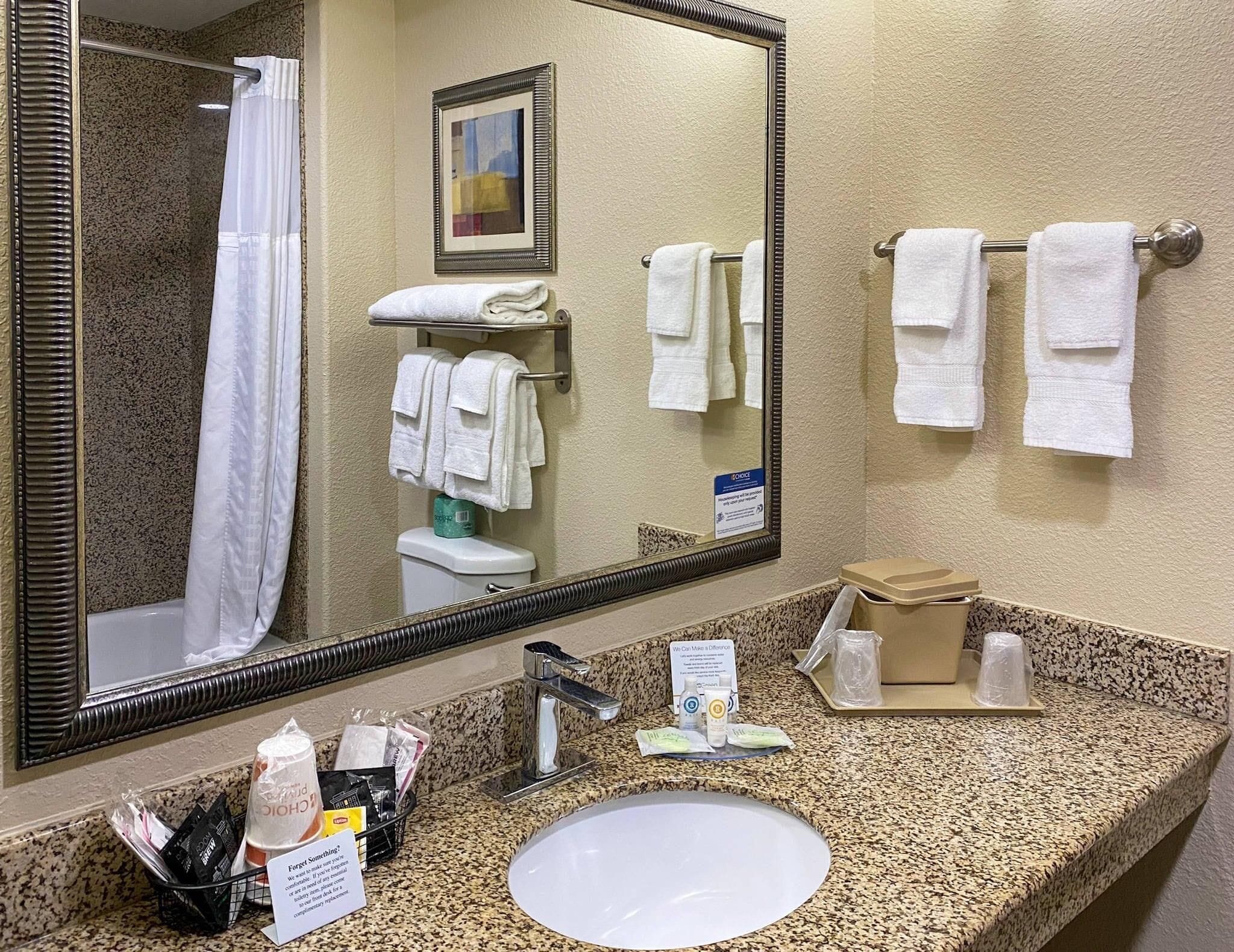 A bathroom with a sink, mirror, towel rack, and toiletries.
