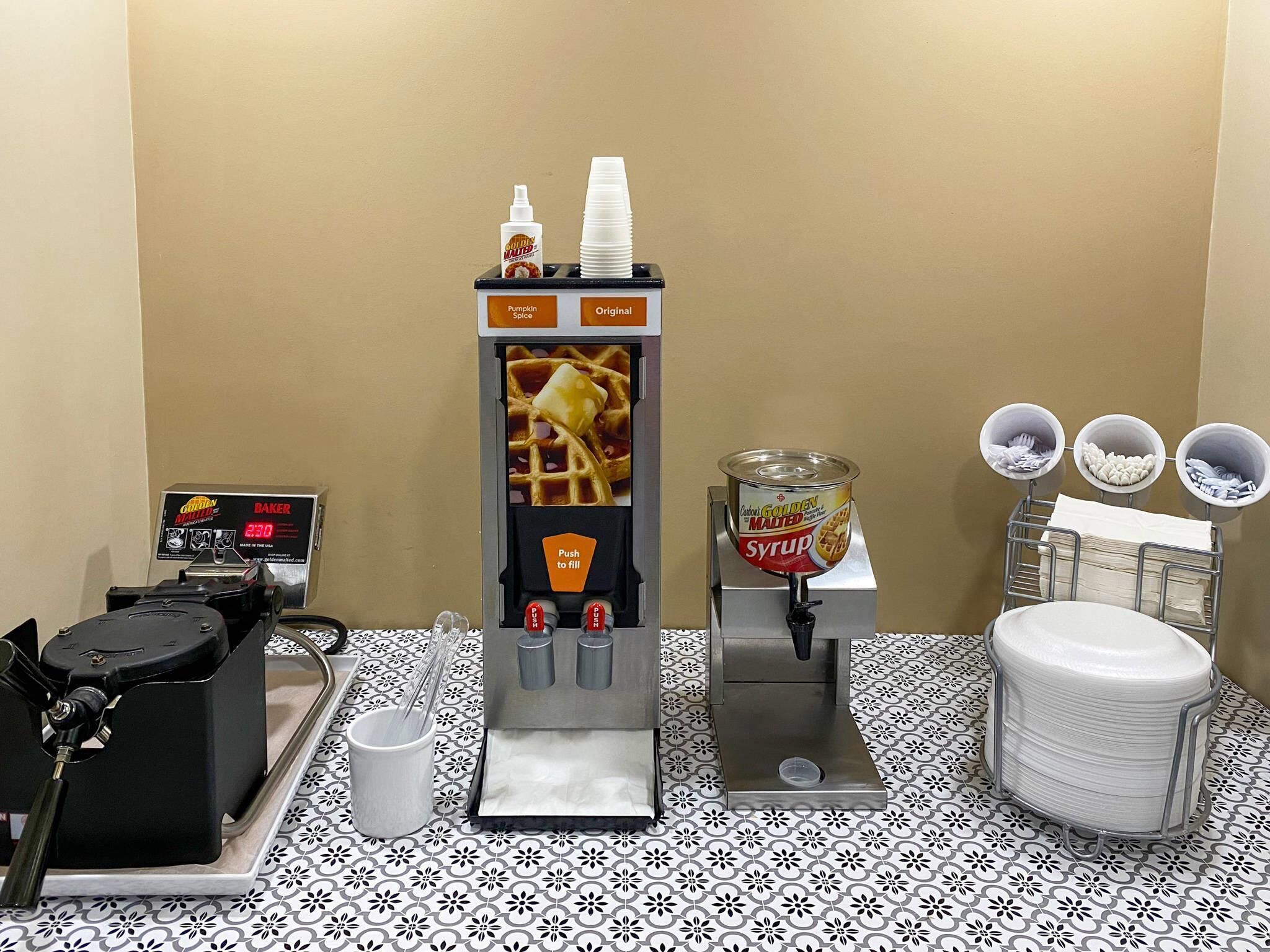 A coffee machine with a syrup dispenser and a waffle maker.