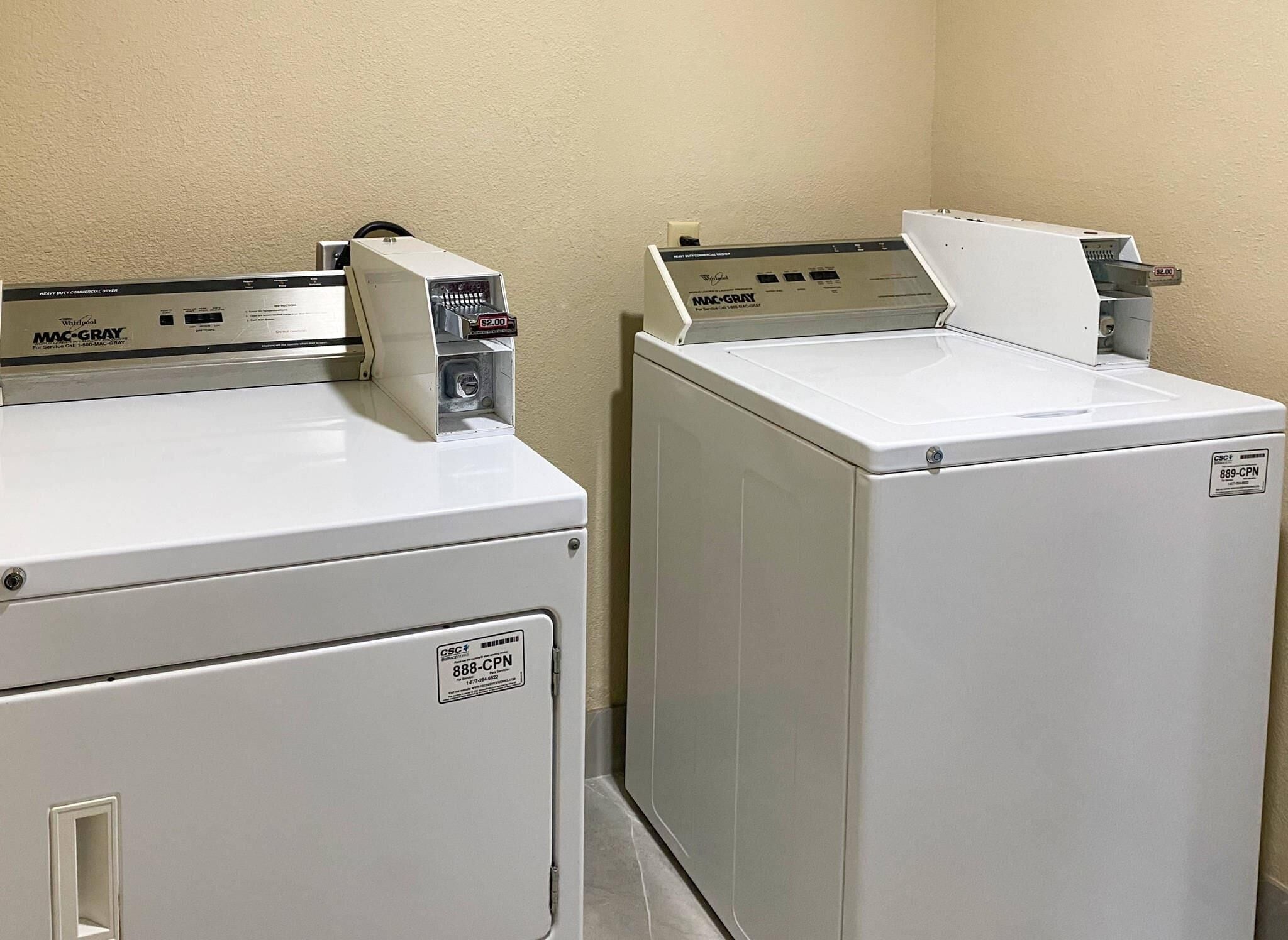 Two front-loading washers with control panels, a wall-mounted dryer, and a visible door handle.