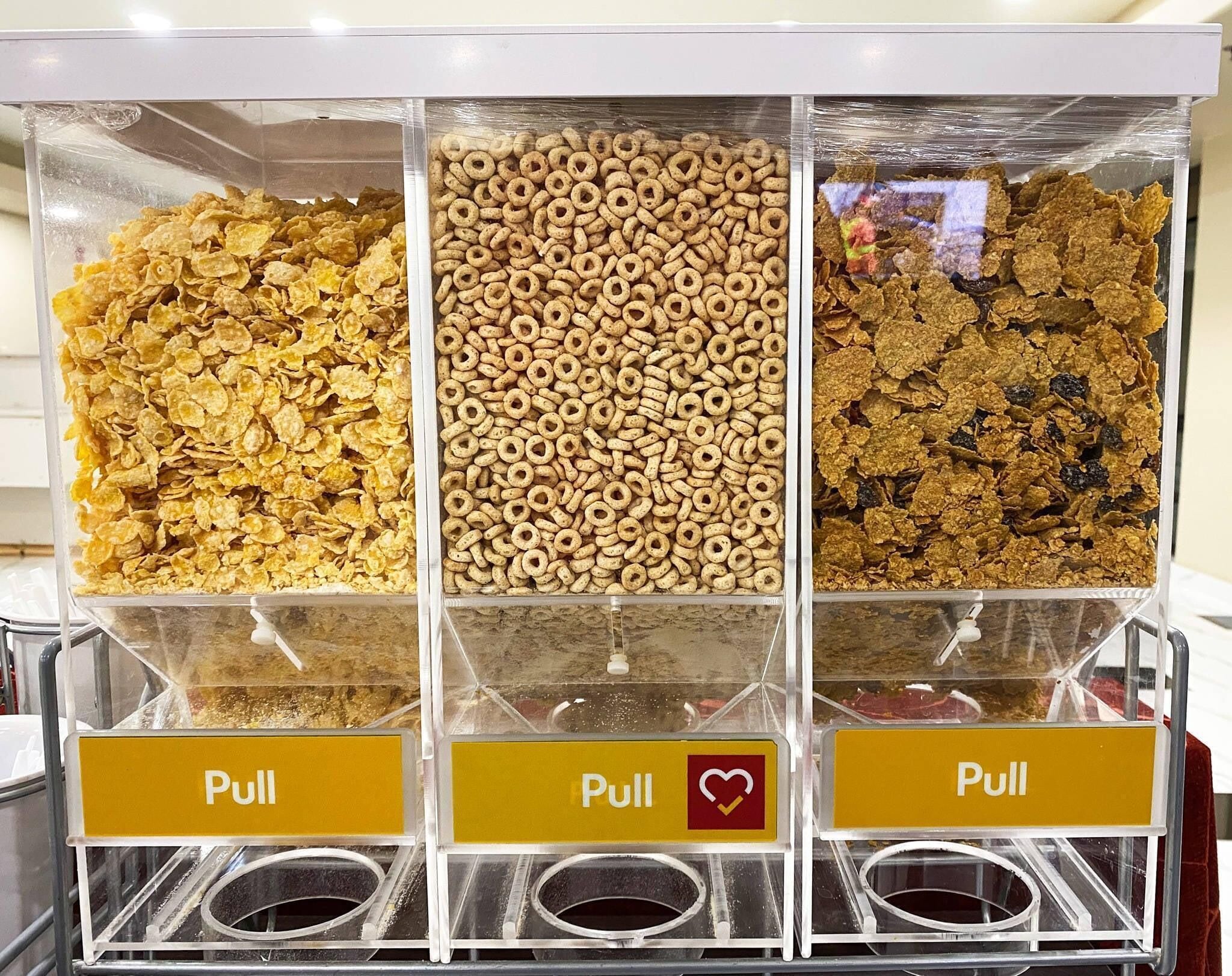 A cereal dispenser with three sections of different cereals and three pull stations.