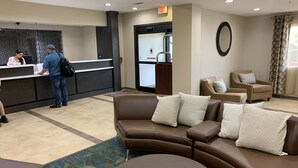 A reception area with a counter, a waiting area with a brown leather sofa and chairs, and a door with an exit sign.