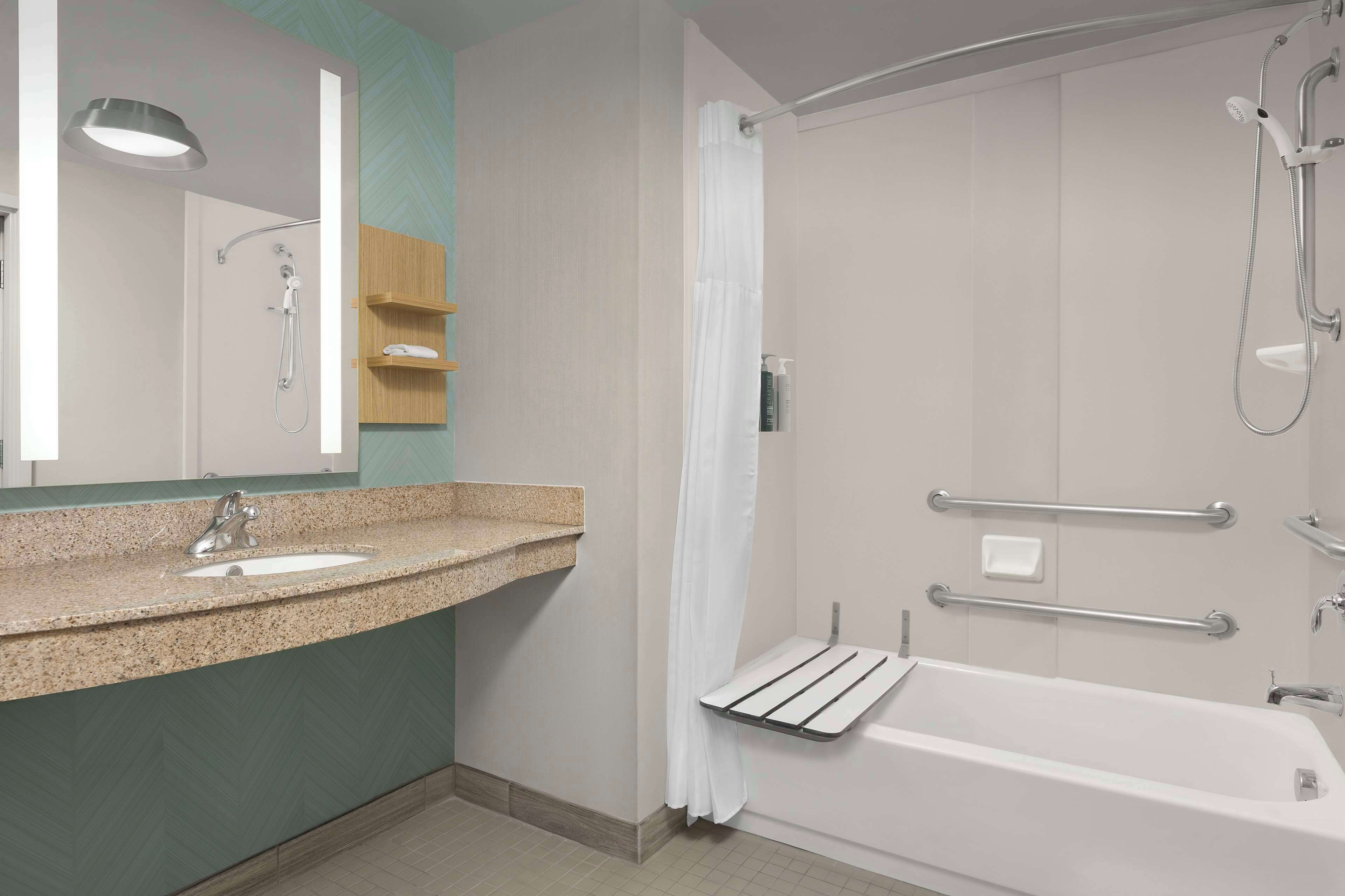 A bathroom with a sink, mirror, shower, and bathtub.