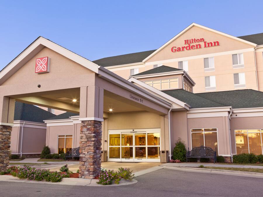A Hilton Garden Inn with a clear entrance, stone pillars, and a large glass door.