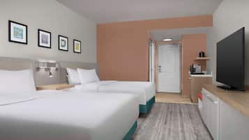 Et hotelværelse med to senge, fjernsyn, skrivebord og tekøkken.