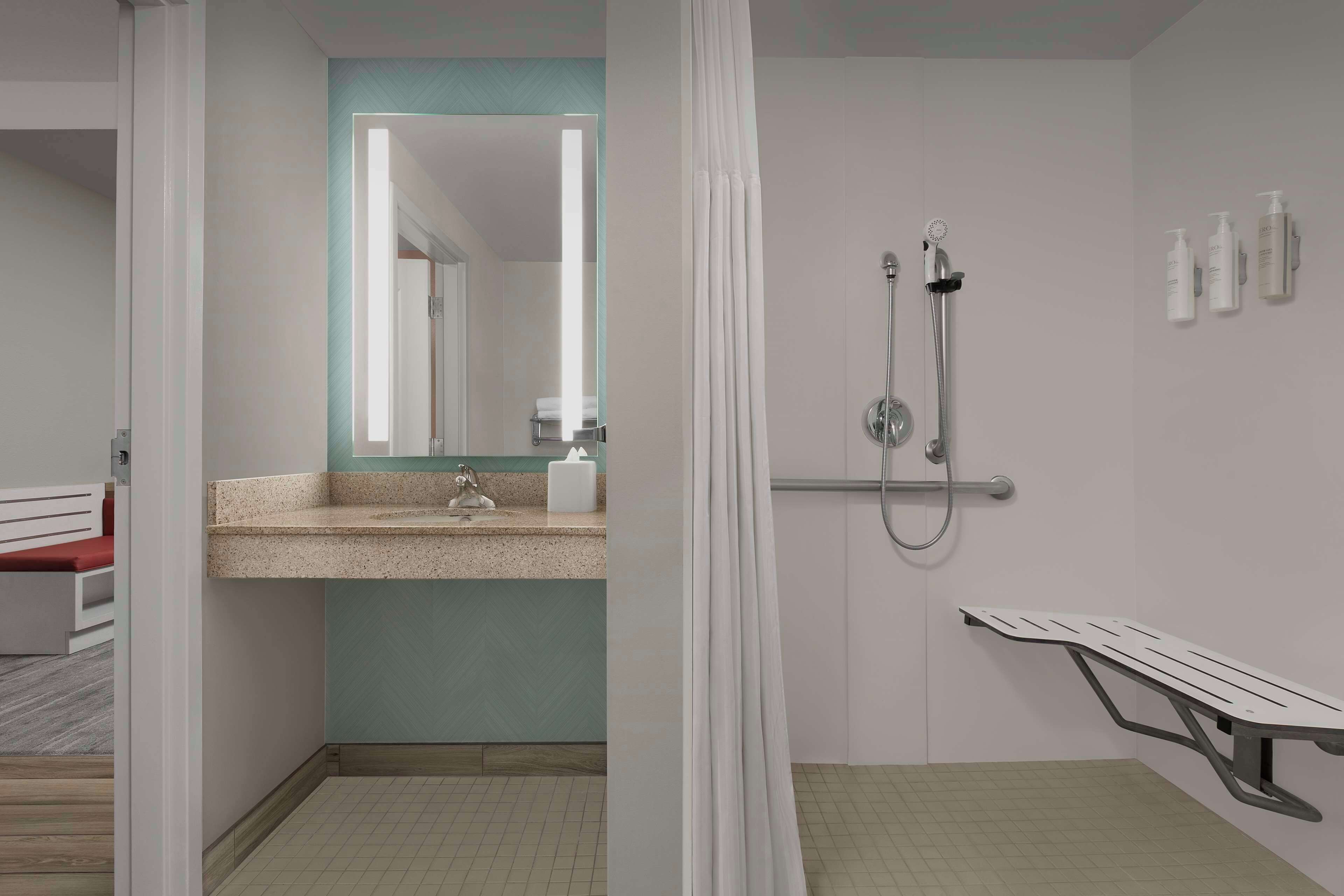 A modern bathroom with a shower, a sink, and a bench.