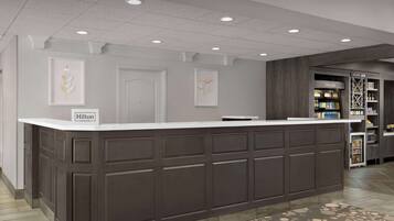 A reception area with a dark wood counter, framed artwork on the walls, and a 'Hilton Honors' sign.