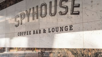 A marble wall with the words "SPYHOUSE COFFEE BAR & LOUNGE" in large letters.