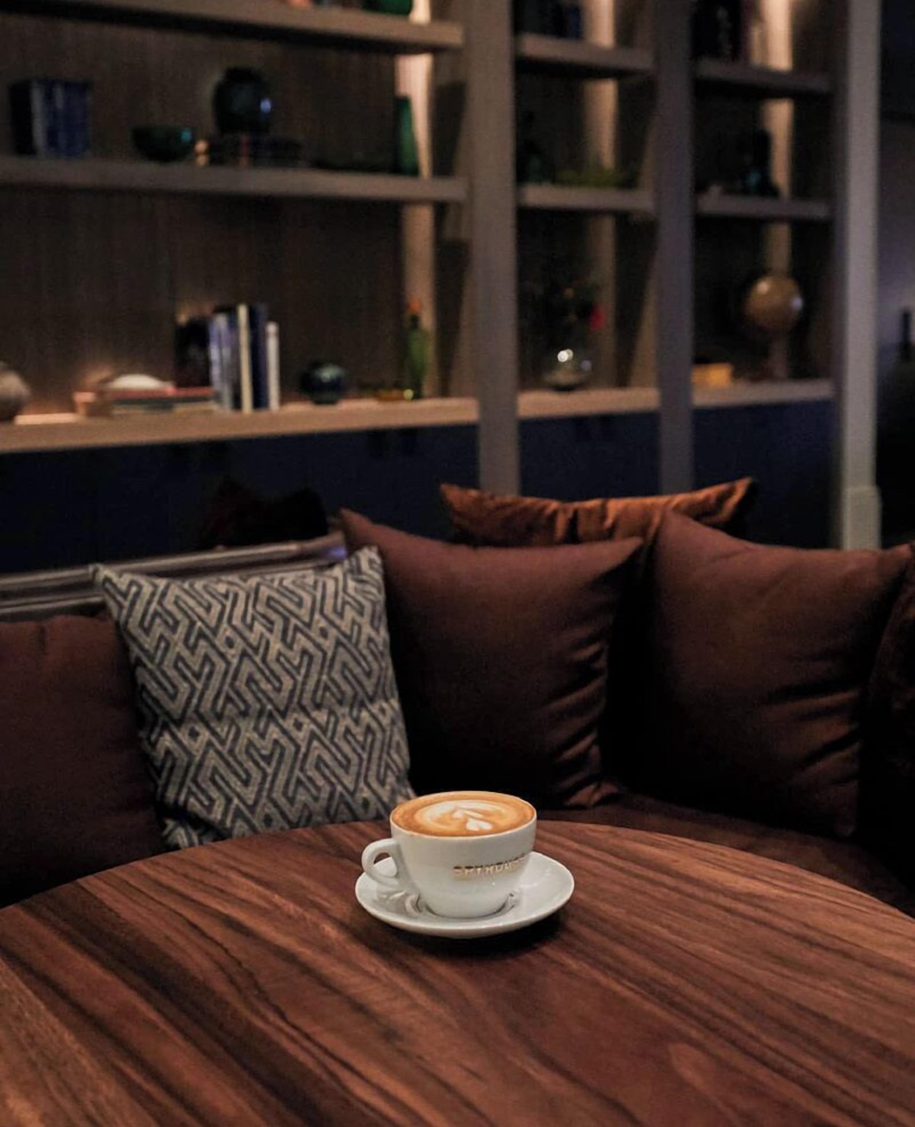 A cozy seating area with a round table, a cup of coffee, and a patterned pillow.