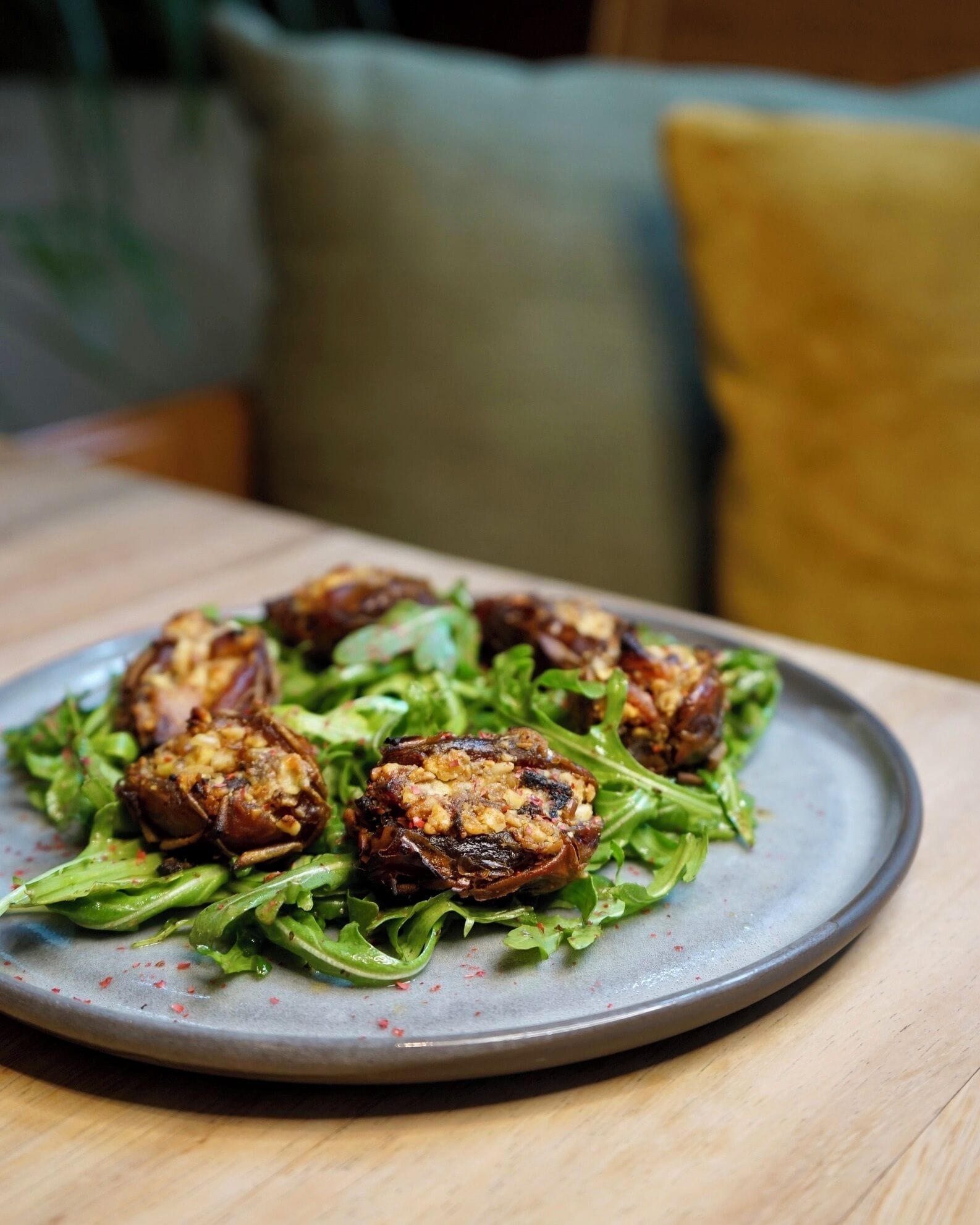 A plate of stuffed mushrooms on a bed of greens, served on a ceramic plate.