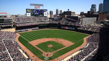 A baseball stadium with multiple seating levels, a large scoreboard, and a cityscape in the background.