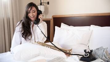 A hotel room with a bed, a telephone, a trumpet, and newspapers.