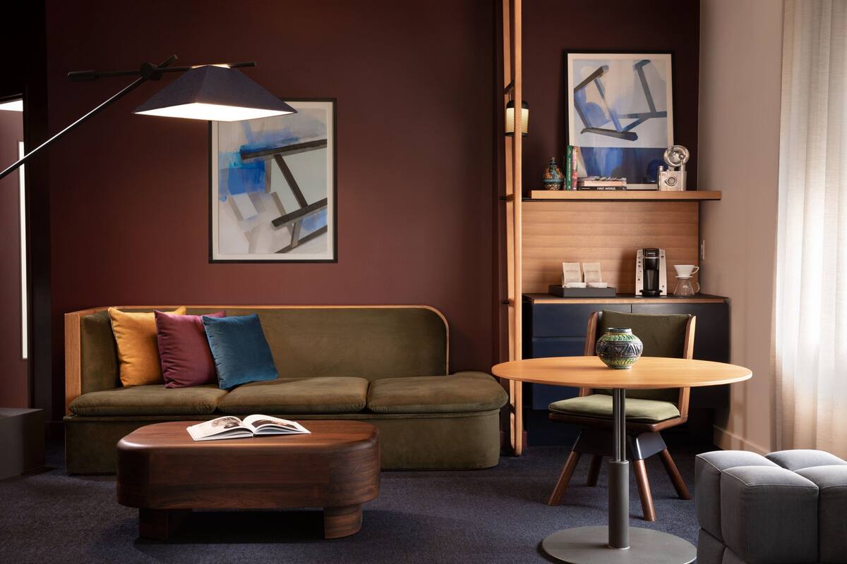 A modern living room with a sofa, ottoman, and a round table.