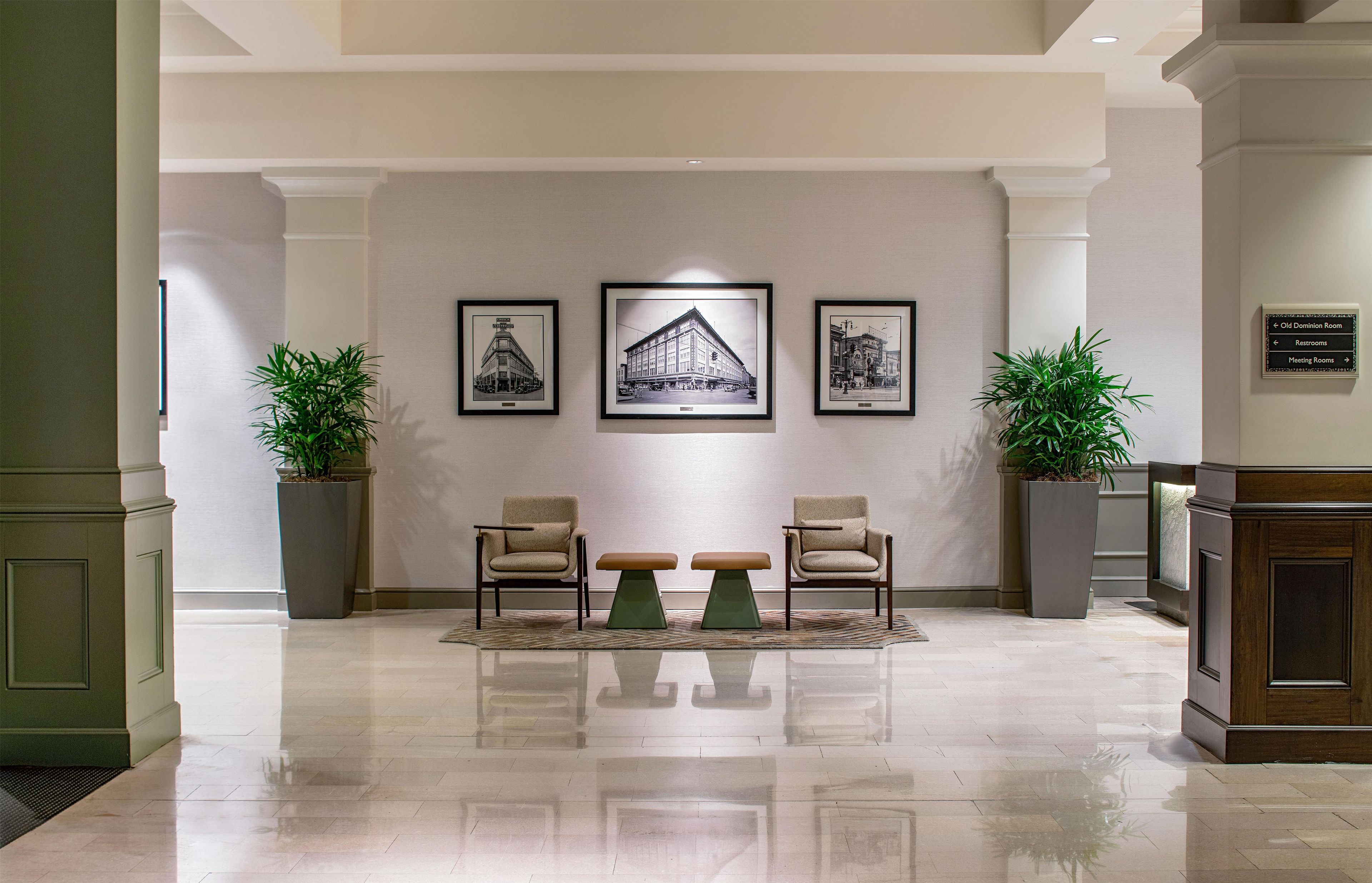 A lobby with two armchairs, a bench, and three framed black and white photographs on the wall.