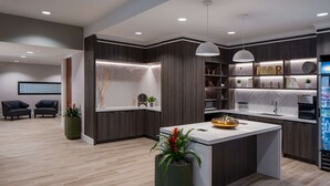 Una cocina moderna con una isla central, electrodomésticos integrados y una zona de estar con sillas.