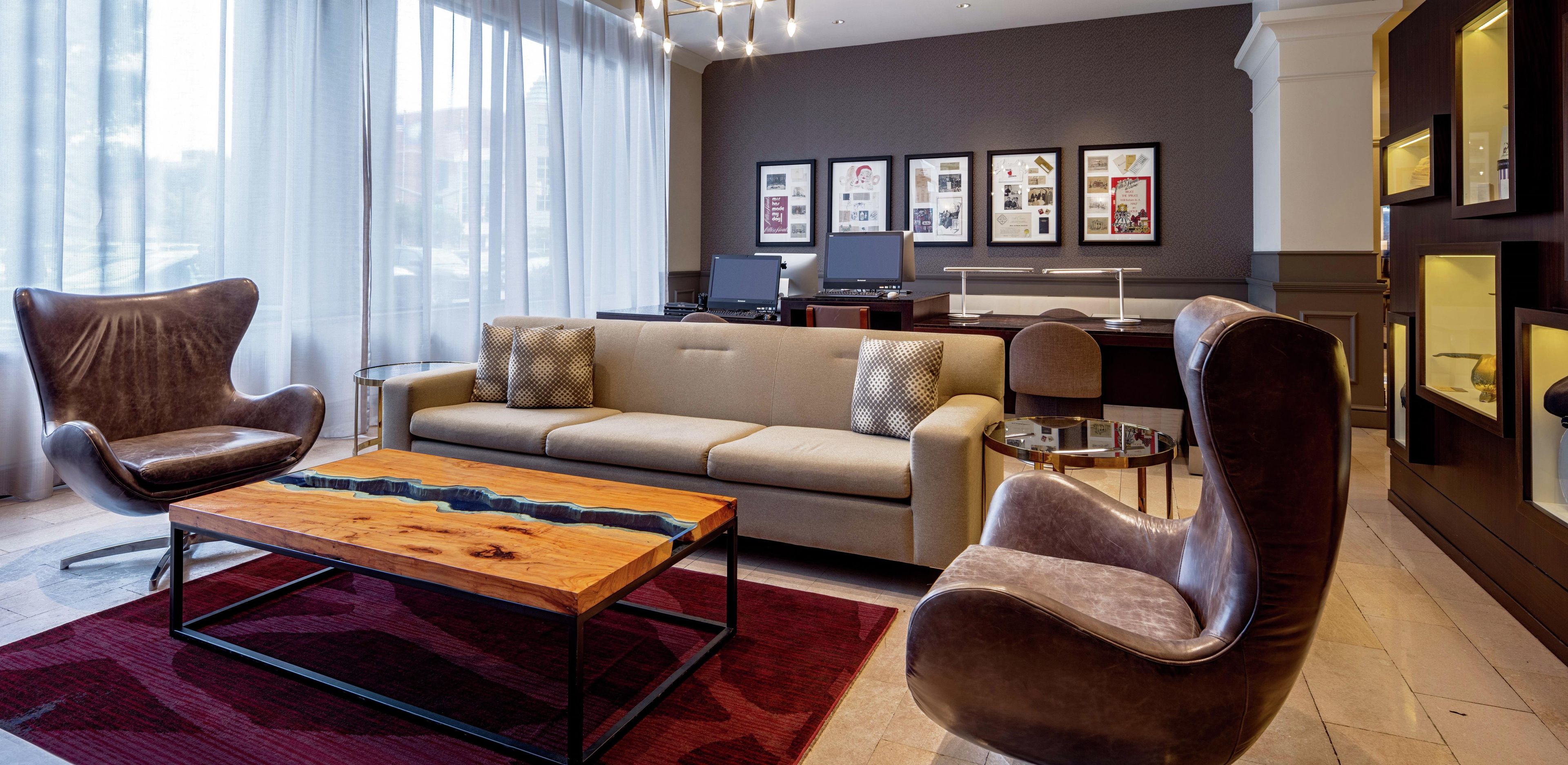 A modern living room with a sofa, two armchairs, a coffee table, and a desk with a computer.