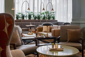 A modern living room with a sofa, armchairs, a coffee table, and a bookshelf. - Hilton Richmond Downtown (Richmond)