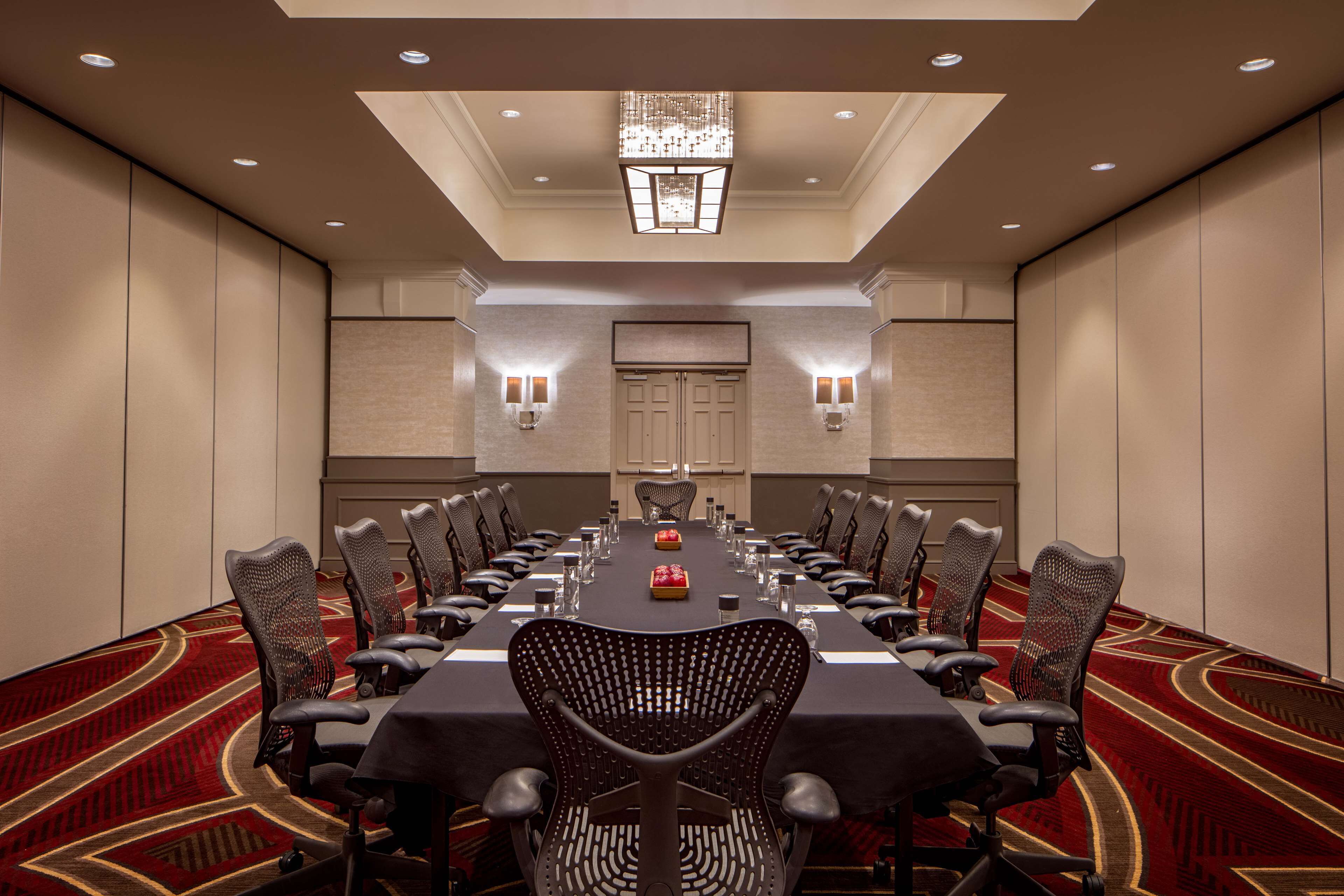 A conference room with a long table, chairs, and a chandelier.