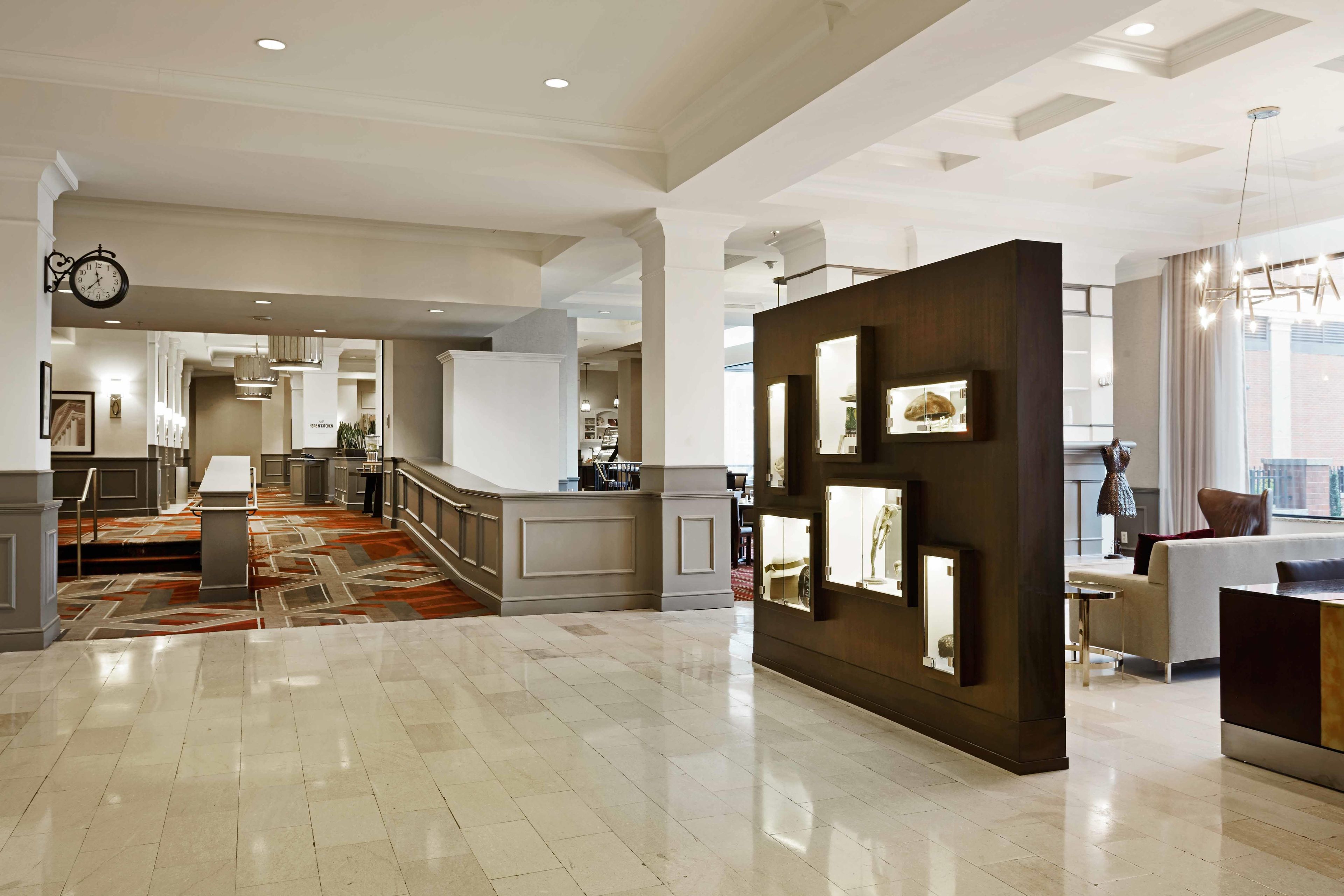 A spacious lobby with a marble floor, a reception desk, and a large wall with framed artwork.