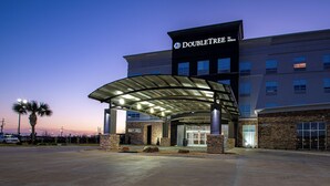 Een hotelentree met een overdekte doorgang, een gevel van natuursteen en een bord met 'DoubleTree by Hilton'.