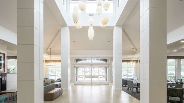 A spacious lobby with a high ceiling, large windows, and a central double door.