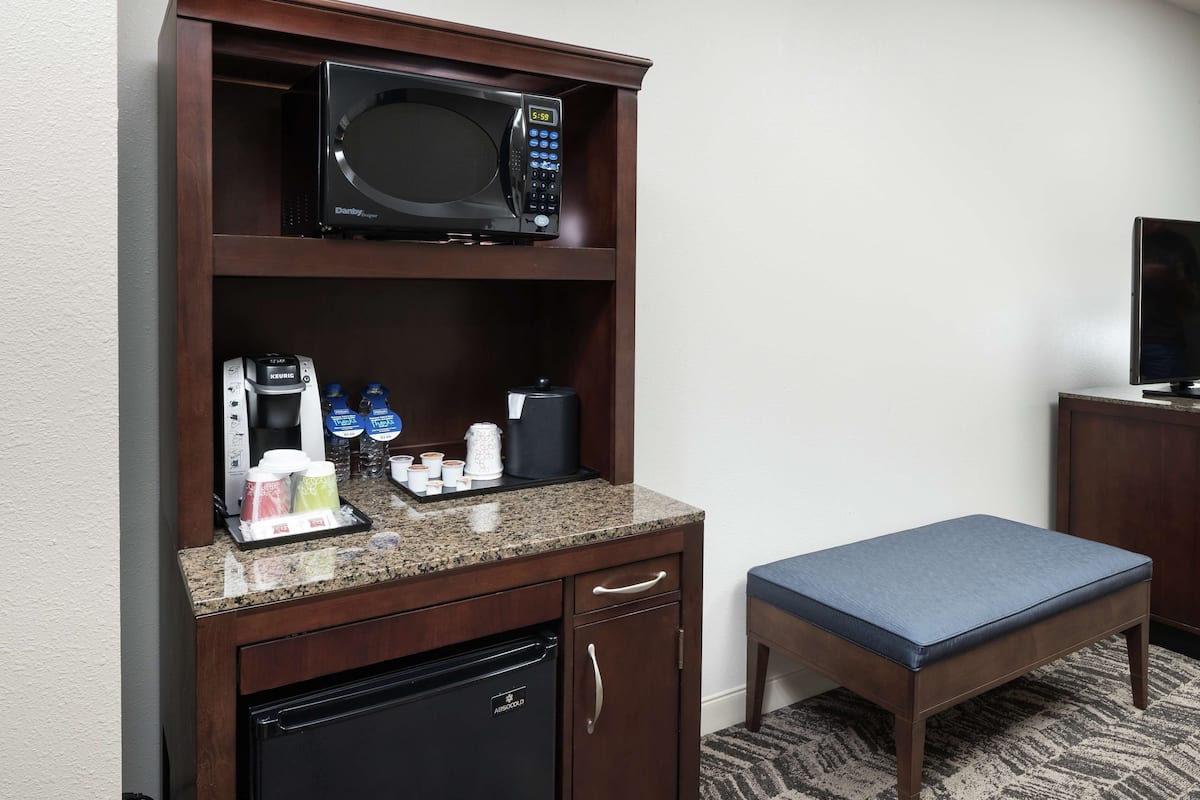 A compact kitchenette with a microwave, coffee maker, and refrigerator.