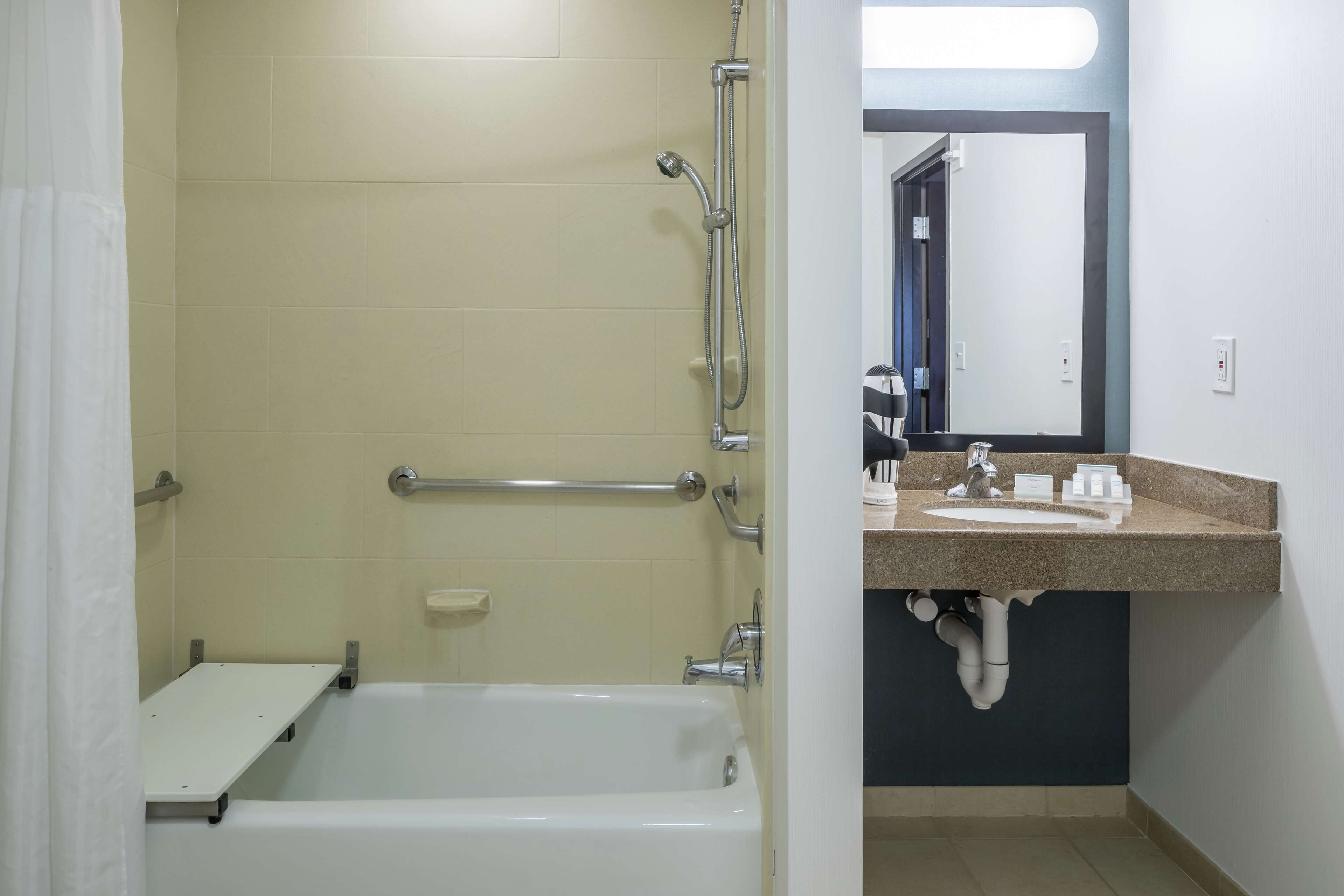 A bathroom with a bathtub, a shower, a sink, and a mirror.
