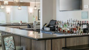 A bar area with a variety of liquor bottles, a cash register, and pendant lighting.