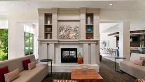 A modern living room with a fireplace, sofas, and a coffee table. - Hilton Garden Inn Charlotte/Ayrsley (Charlotte)