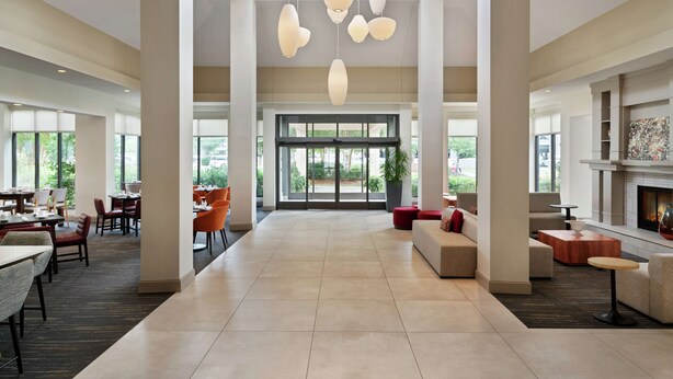 A spacious lobby with high ceilings, modern pendant lighting, and a fireplace. - Hilton Garden Inn Charlotte/Ayrsley (Charlotte)