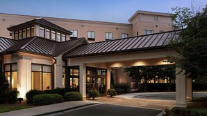A hotel with a modern design, featuring a covered entrance, large windows, and a landscaped driveway. - Hilton Garden Inn Charlotte/Ayrsley (Charlotte)