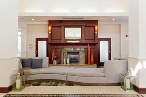 A modern living room with a fireplace, a sofa, and decorative items. - Hilton Garden Inn Winchester (Winchester)