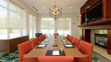 A conference room with a long table, orange chairs, and a fireplace.