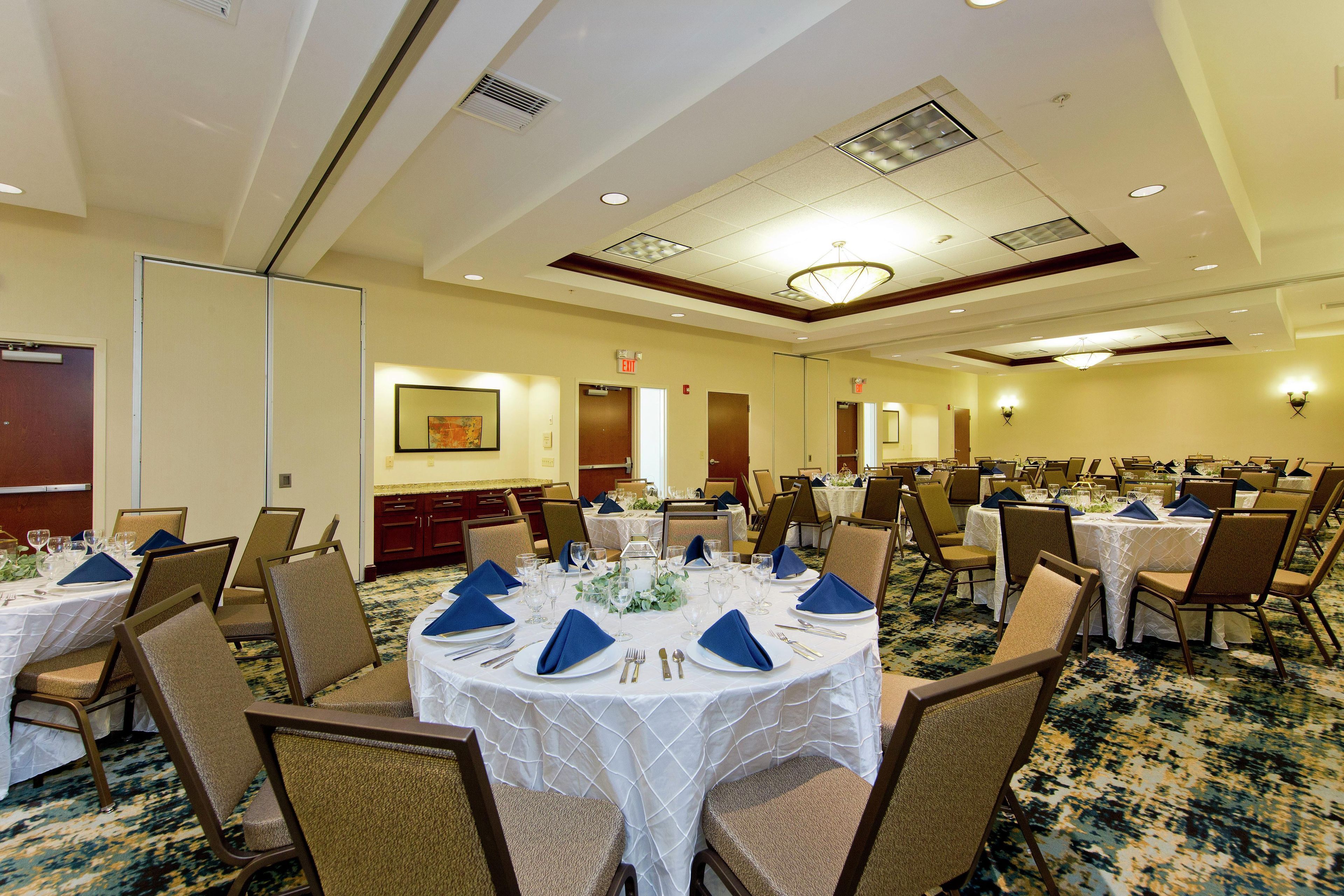 A conference room with round tables, chairs, and a carpeted floor.