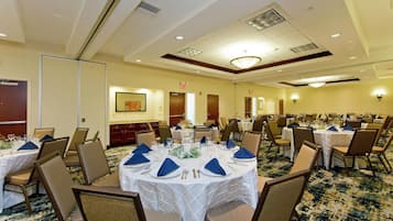 A conference room with round tables, chairs, and a carpeted floor.