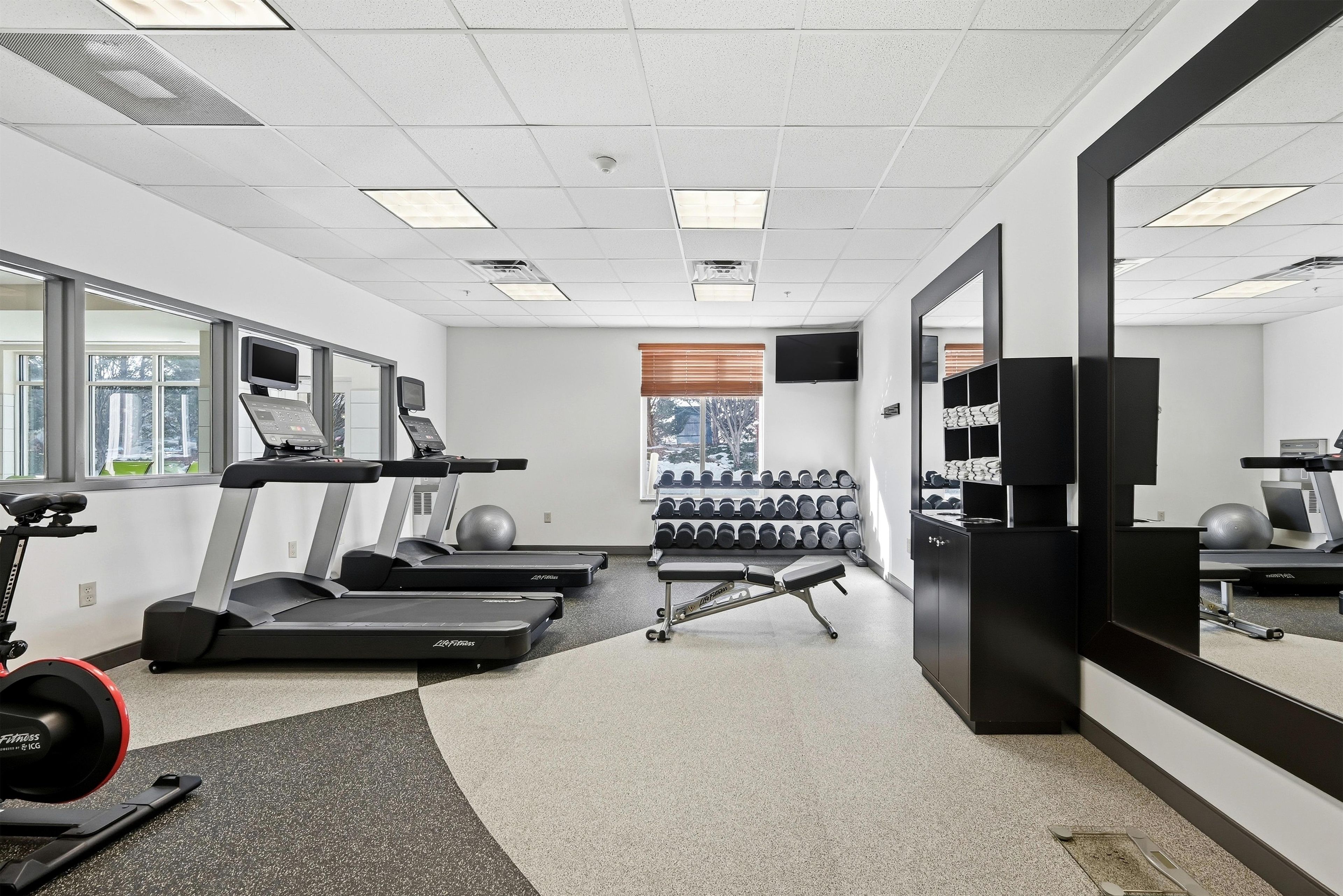 A gym with treadmills, exercise balls, and dumbbells.