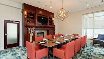 A conference room with a long table, red chairs, a fireplace, and a large window.