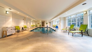 A spacious indoor pool area with multiple seating areas and a clear view of the outdoors through large windows. - Hilton Garden Inn Winchester (Winchester)