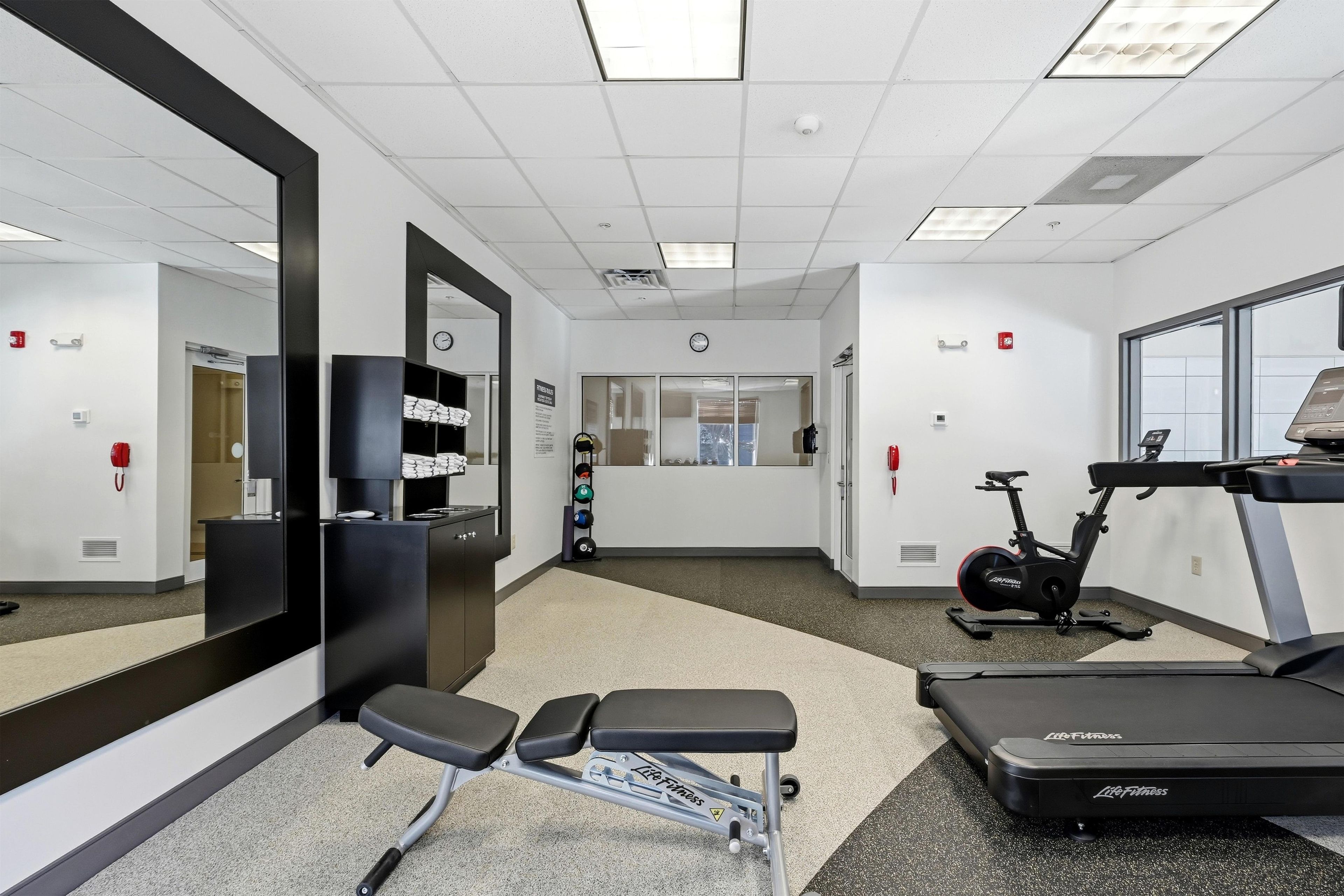 A gym with exercise equipment, a treadmill, and a bench.
