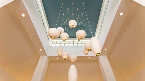 A modern interior with a geometric ceiling design, recessed lighting, and hanging pendant lights. - Hilton Garden Inn Winchester (Winchester)