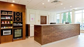 A reception area with a wooden reception desk, a wine cooler, and a microwave. - Hilton Garden Inn Winchester (Winchester)