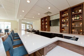 A modern kitchen with a bar area, seating, and a large window. - Hilton Garden Inn Winchester (Winchester)