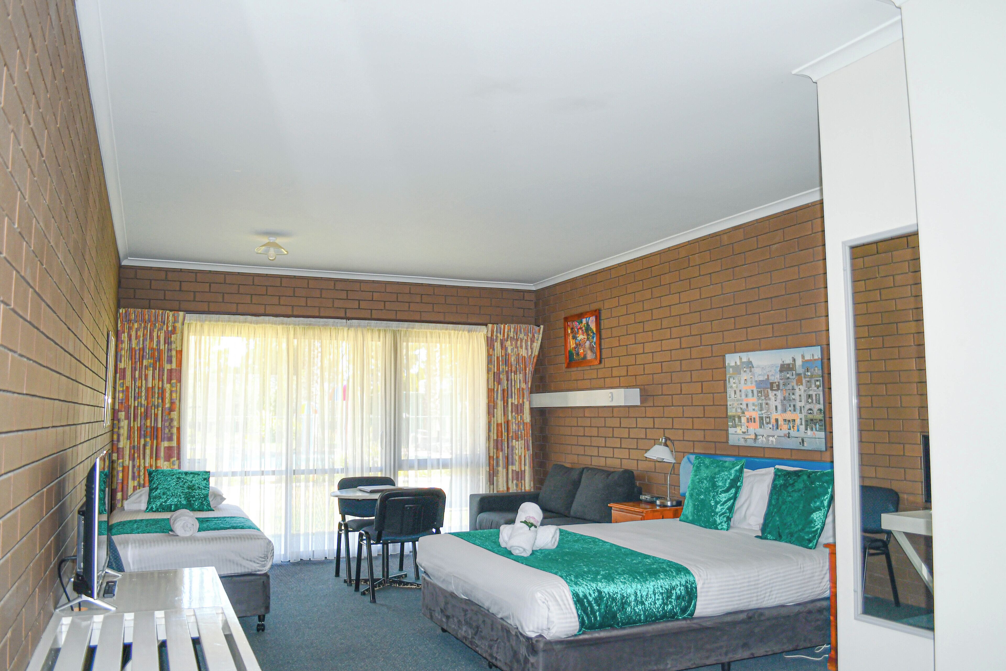 A hotel room with a bed, a desk, a chair, and a sofa.
