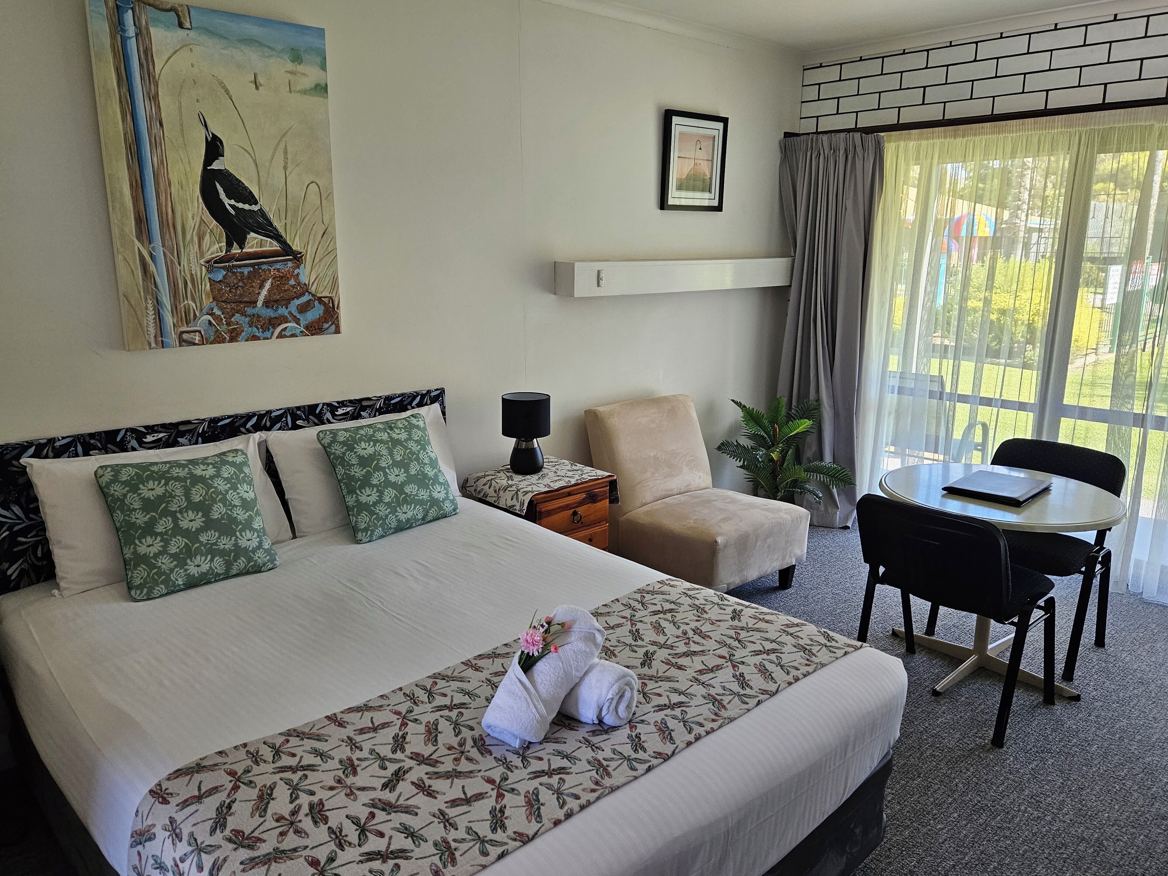 Una habitación de hotel con cama, una silla, una mesa y una ventana con cortinas.