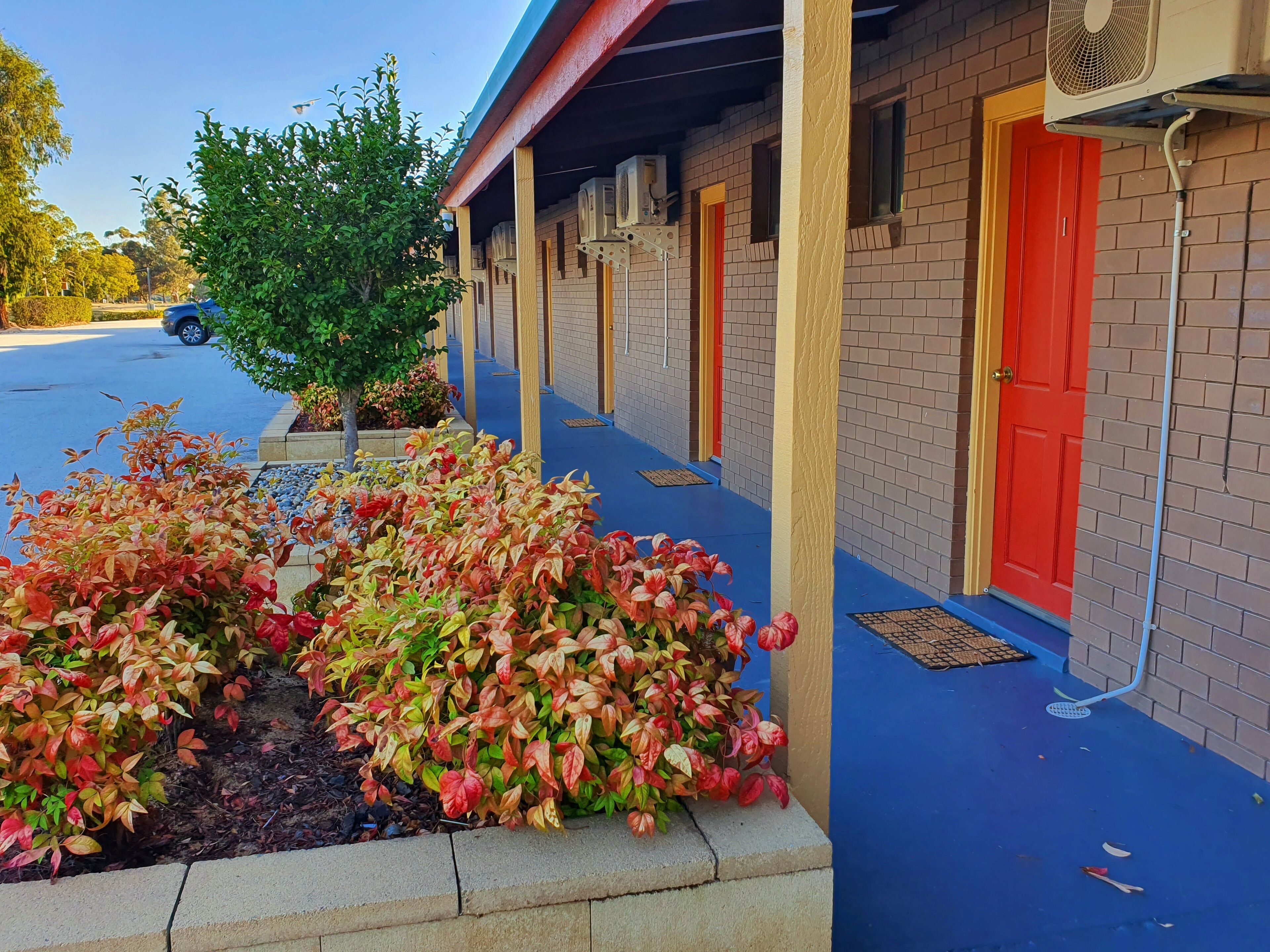 A building with a red door, air conditioning units, and a blue awning.