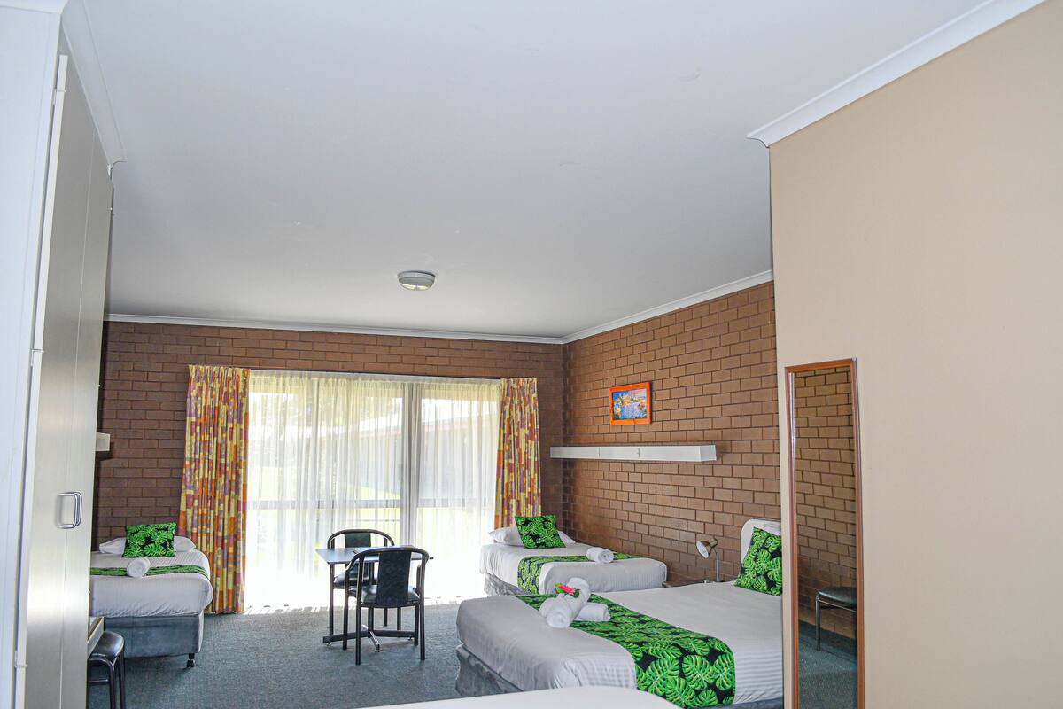 A hotel room with two beds, a desk, a chair, and a mirror.